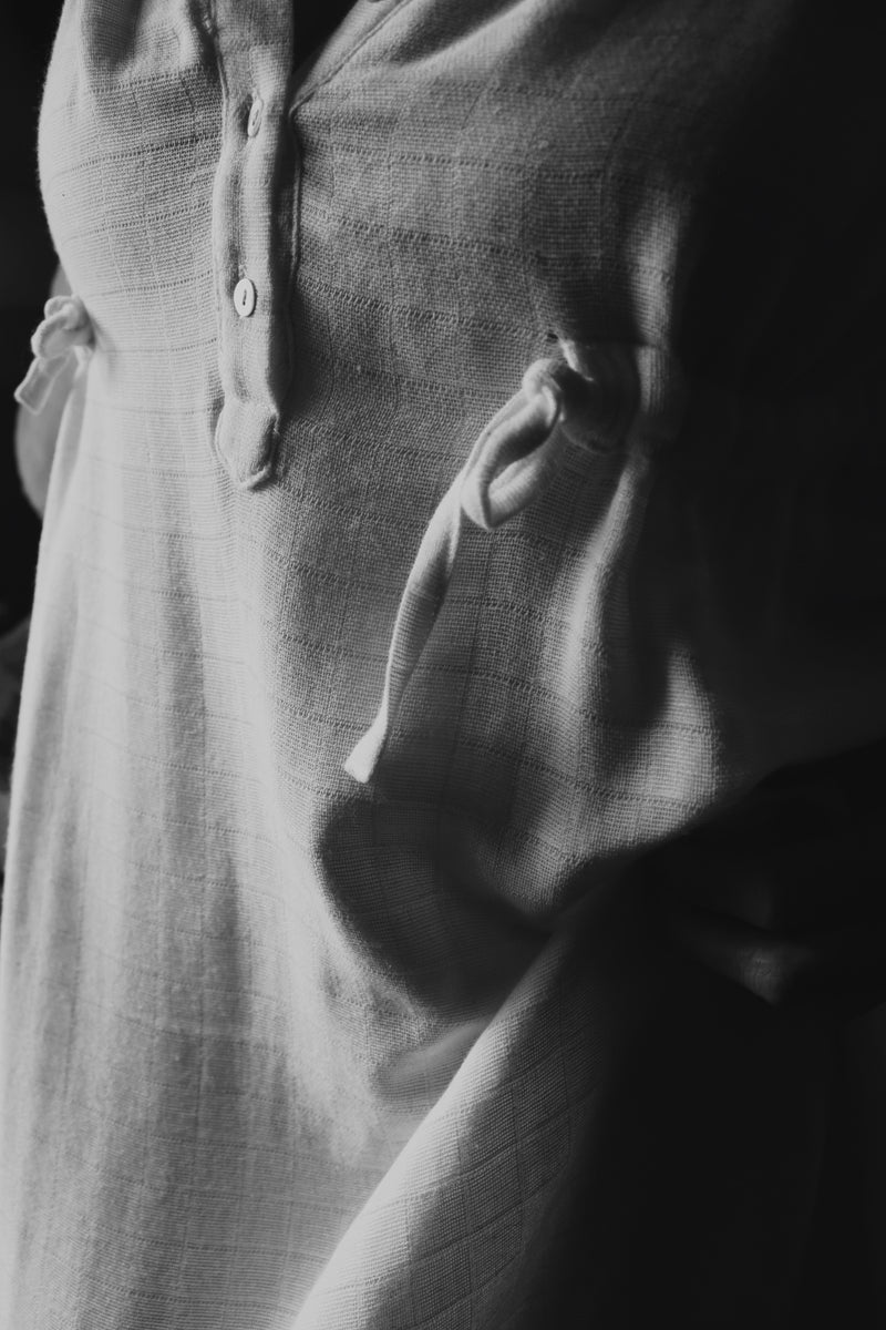 Close-up of The Lydia cotton-bamboo dress fabric texture and side tie detail, black and white editorial