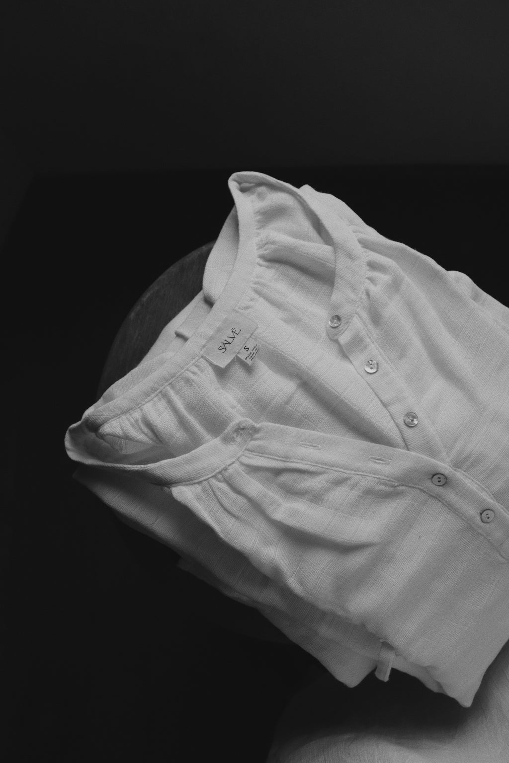 The Lydia cotton-bamboo dress folded with Salvē label visible, black and white product detail shot