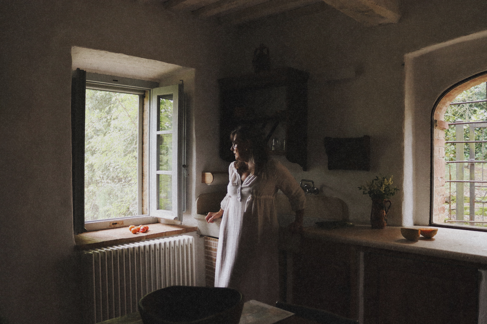 Woman in The Lydia cotton-bamboo dress standing at an open window in a Tuscan farmhouse kitchen, soft natural light