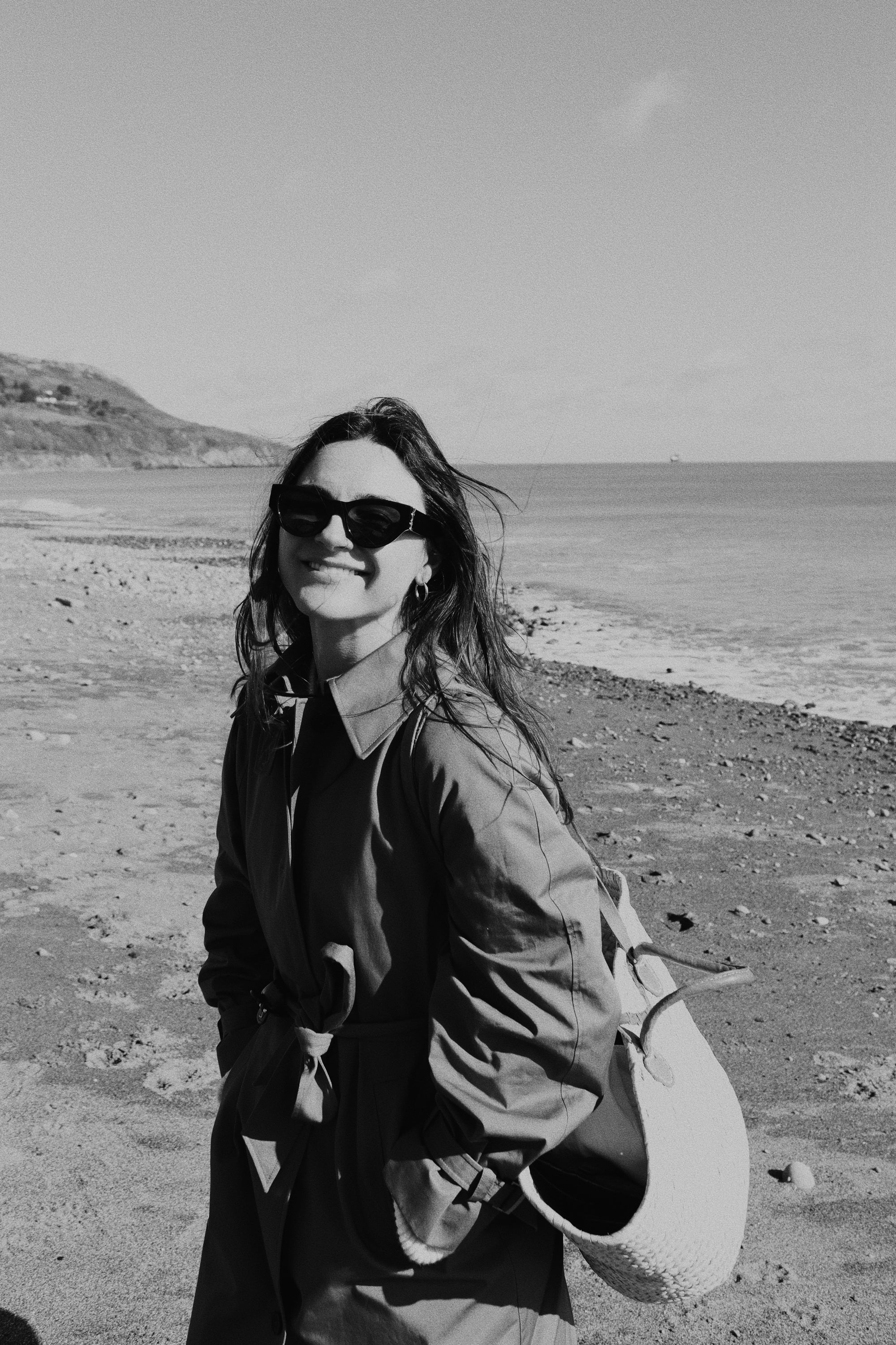 Serena, the founder of salve, stands on a beach in Ireland smiling at the camera
